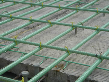 A layer of epoxy coated reinforcing steel mesh is placed on the concrete.